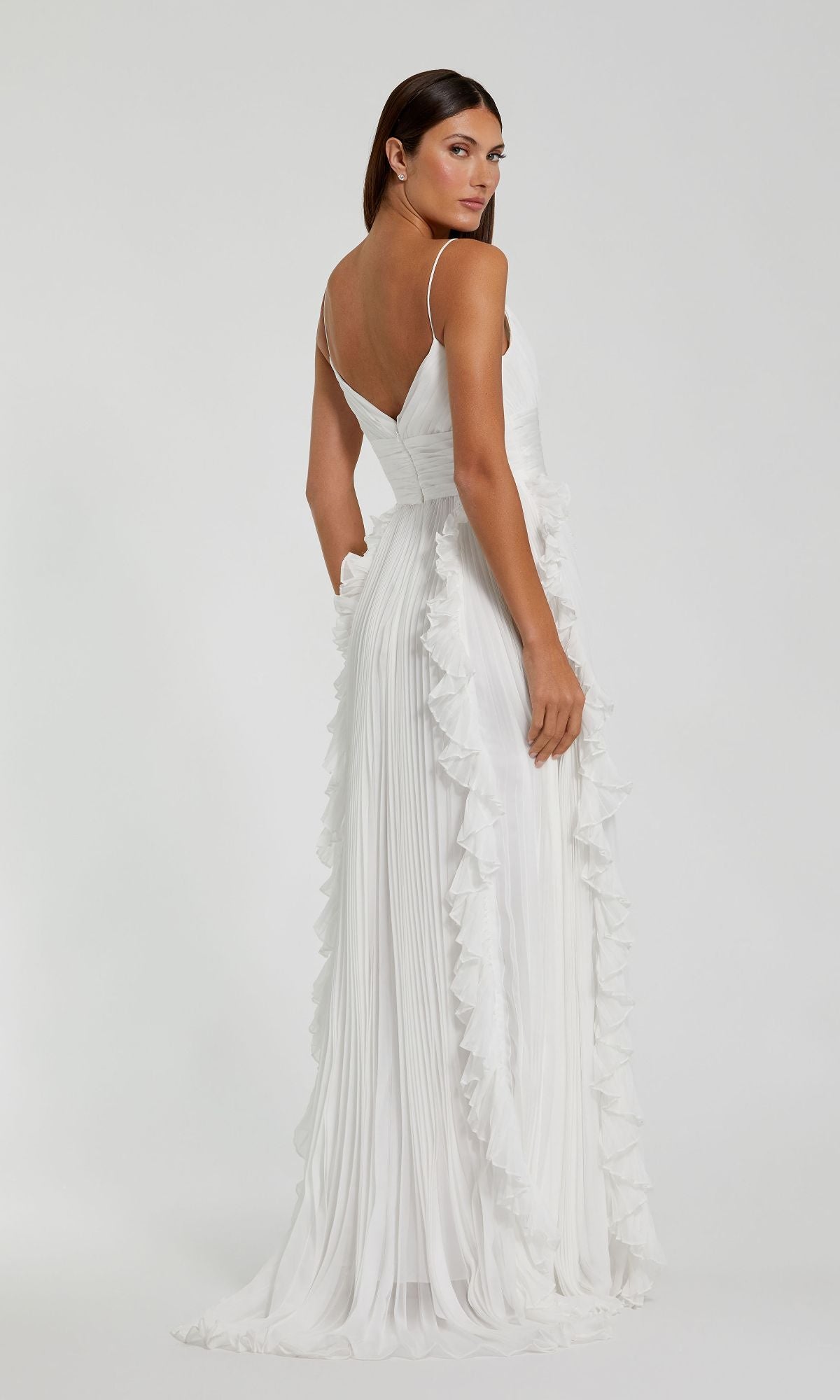 A woman models the Ruffled Long White Formal Dress 49533, standing with her back to the camera and glancing over her shoulder against a plain background.